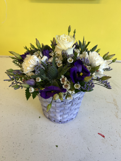 Scottish Basket - A small purple woven basket with a scottish themed arrangement on top including a white rose, thistles and splashes of purple throughout.